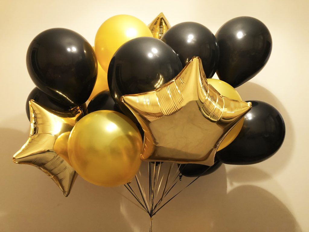 Black and gold helium balloons, as well as gold stars. Expensive and rich surprise for the celebration of a significant event